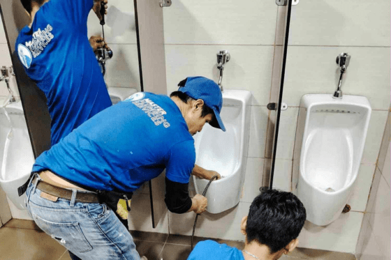 Team of industrial plumbers performing pipe maintenance in a factory setting, showcasing specialized commercial plumbing services.
